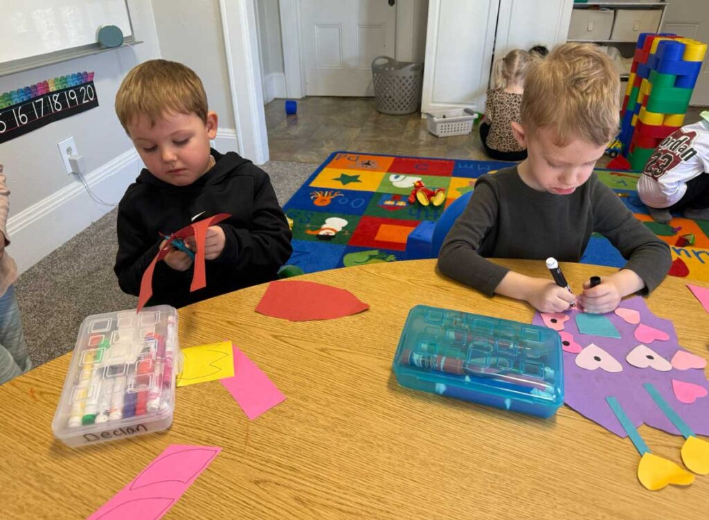 two boys working on cutting and drawing projects at Yellow Brick Road Preschool in Napa