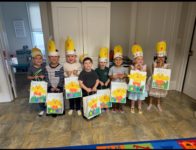 group of children wearing homemade springtime hats and carrying springtime paper bags
