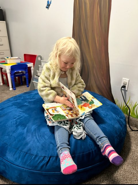 little girl reading on a bean bag chair