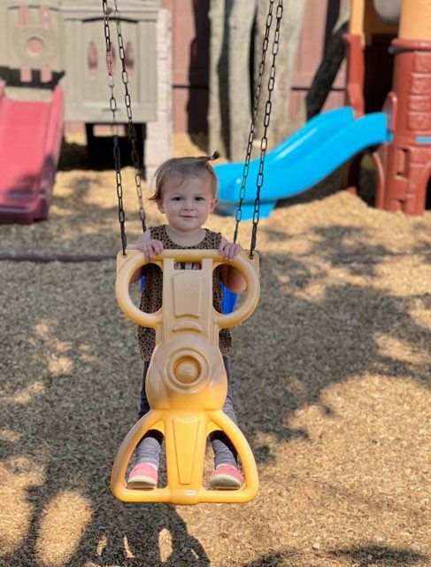 little girl riding on playground toy