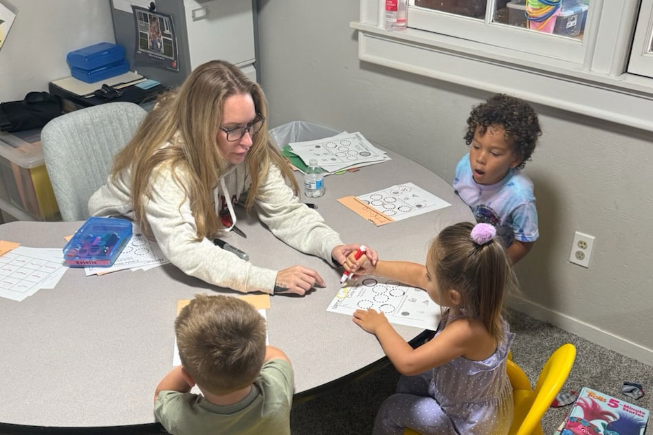 teacher at Yellow Brick Road helping students at a table
